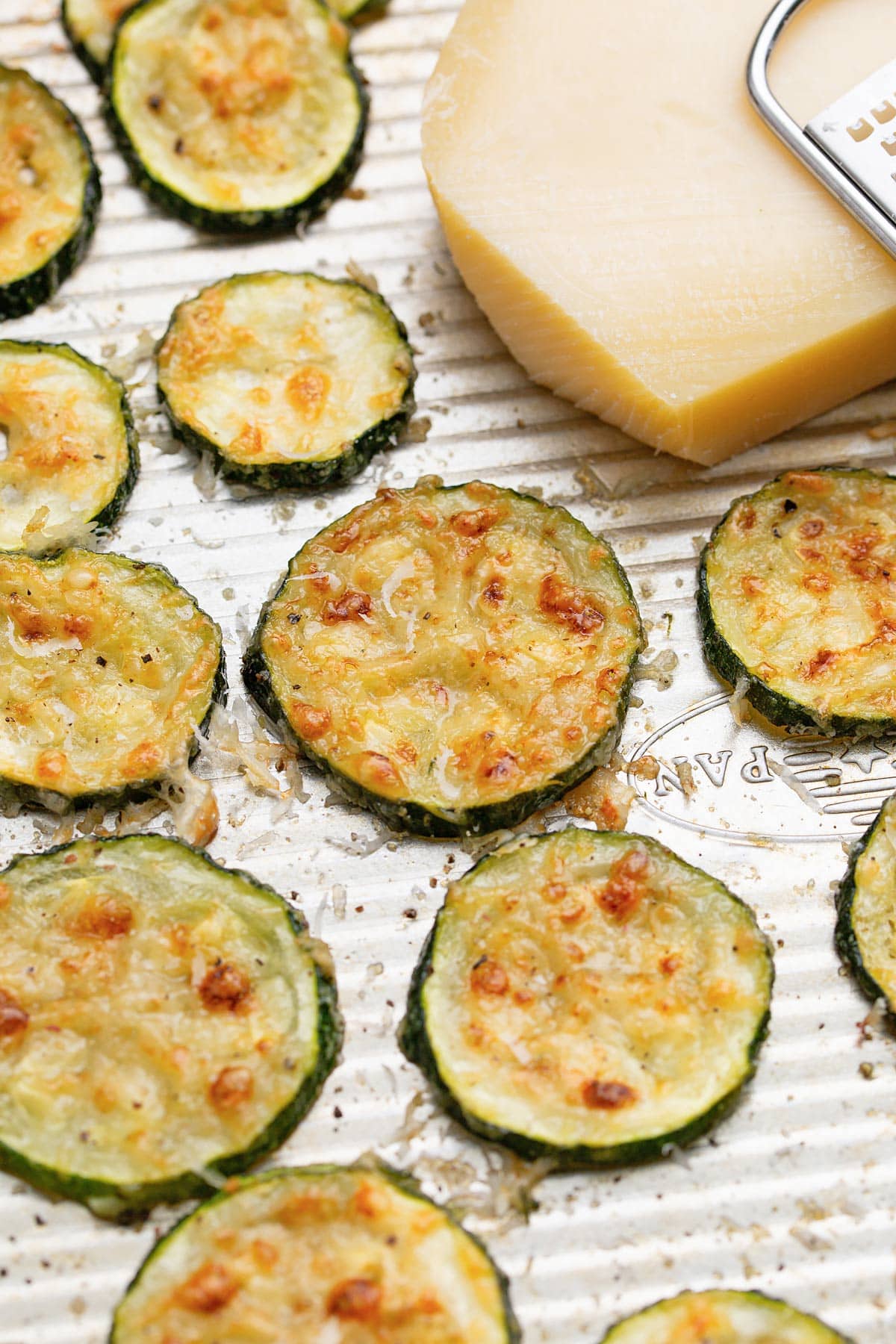 Roasted Parmesan zucchini arranged in a single layer on a ribbed baking sheet.