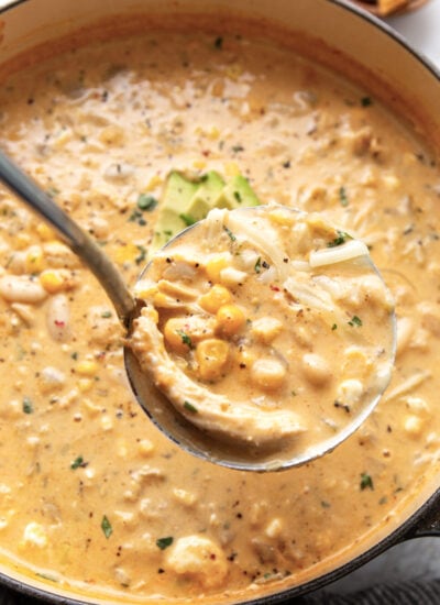 A generous ladle of white chicken chili with shredded chicken, beans, corn and chopped cilantro.