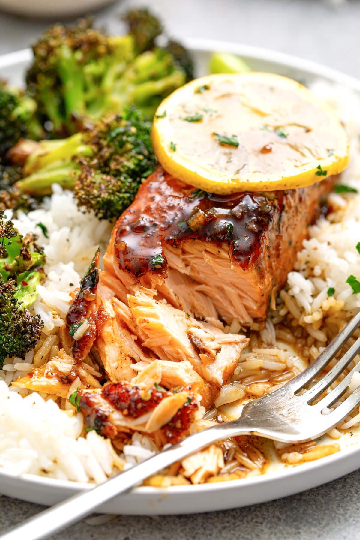 Honey glazed salmon over a bed of white rice and a side of roasted broccoli.