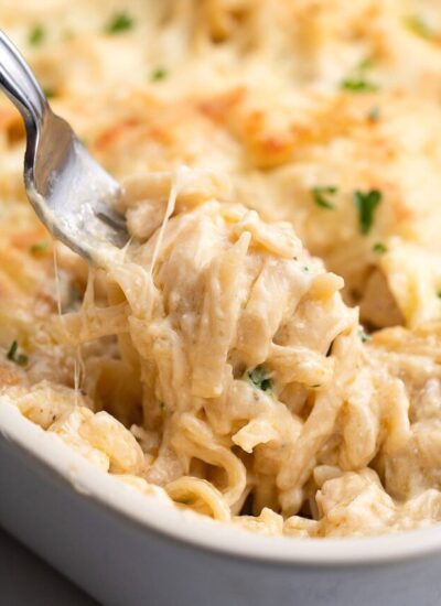 A creamy serving of easy chicken tetrazzini lifted out of the casserole with a fork.