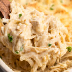 A generous serving of easy chicken tetrazzini lifted out of the casserole with a wooden spoon.