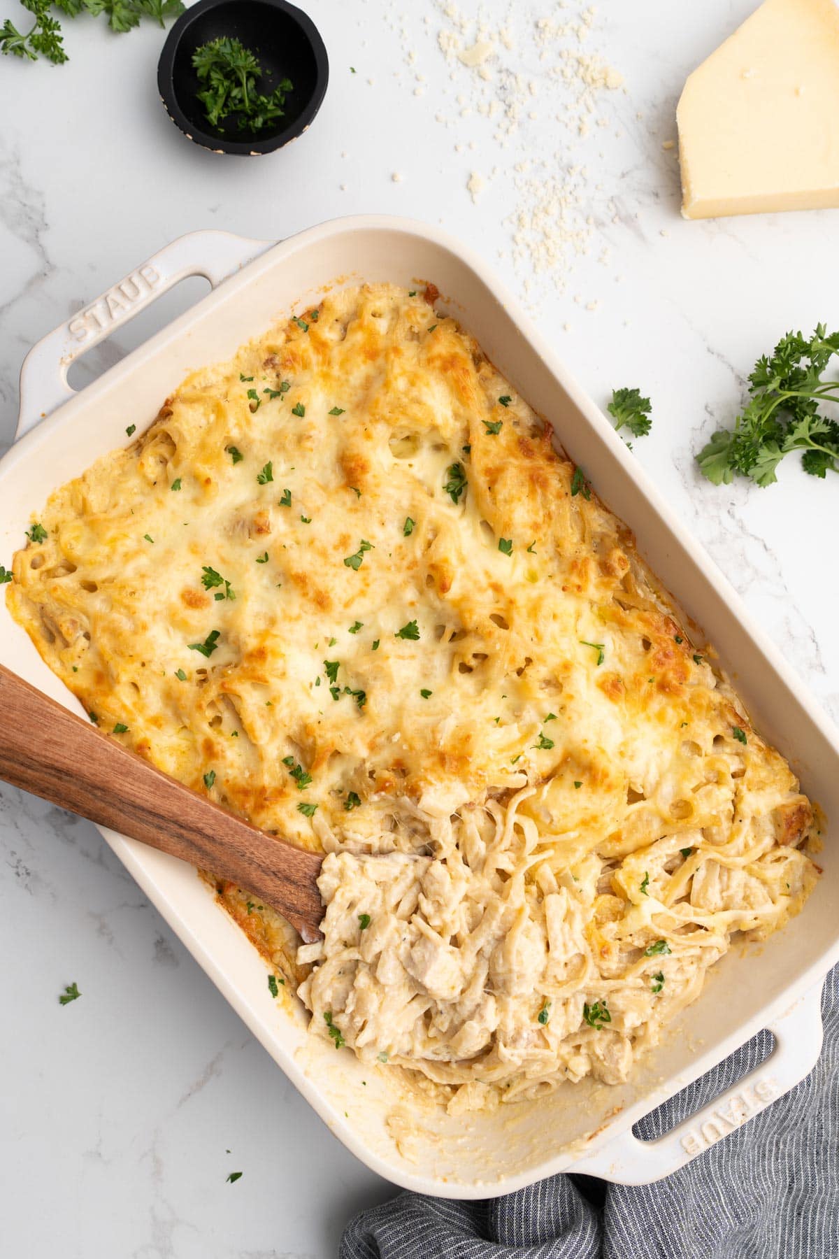 A top down photo of easy chicken tetrazzini topped with fresh chopped parsley in a white casserole dish.