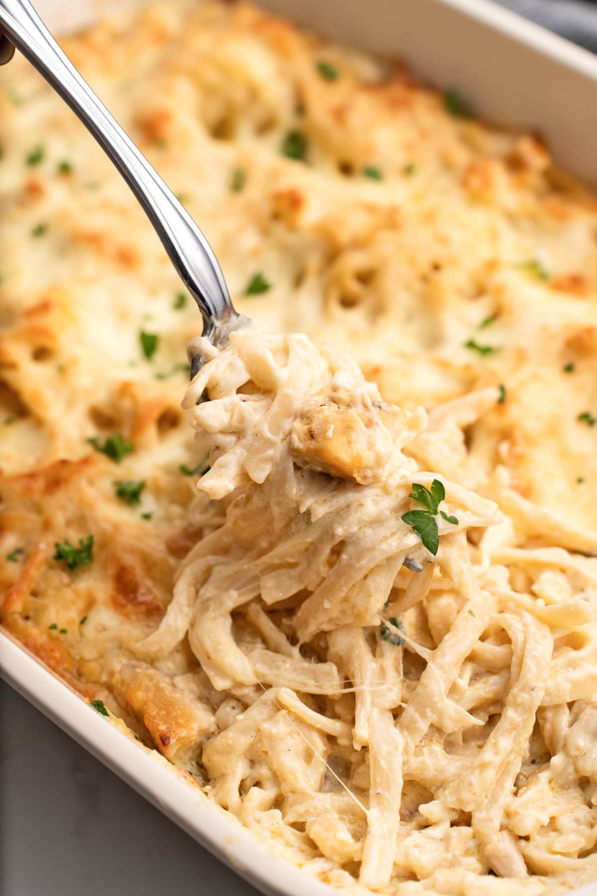 A generous serving of easy chicken tetrazzini lifted out of the casserole with a fork.