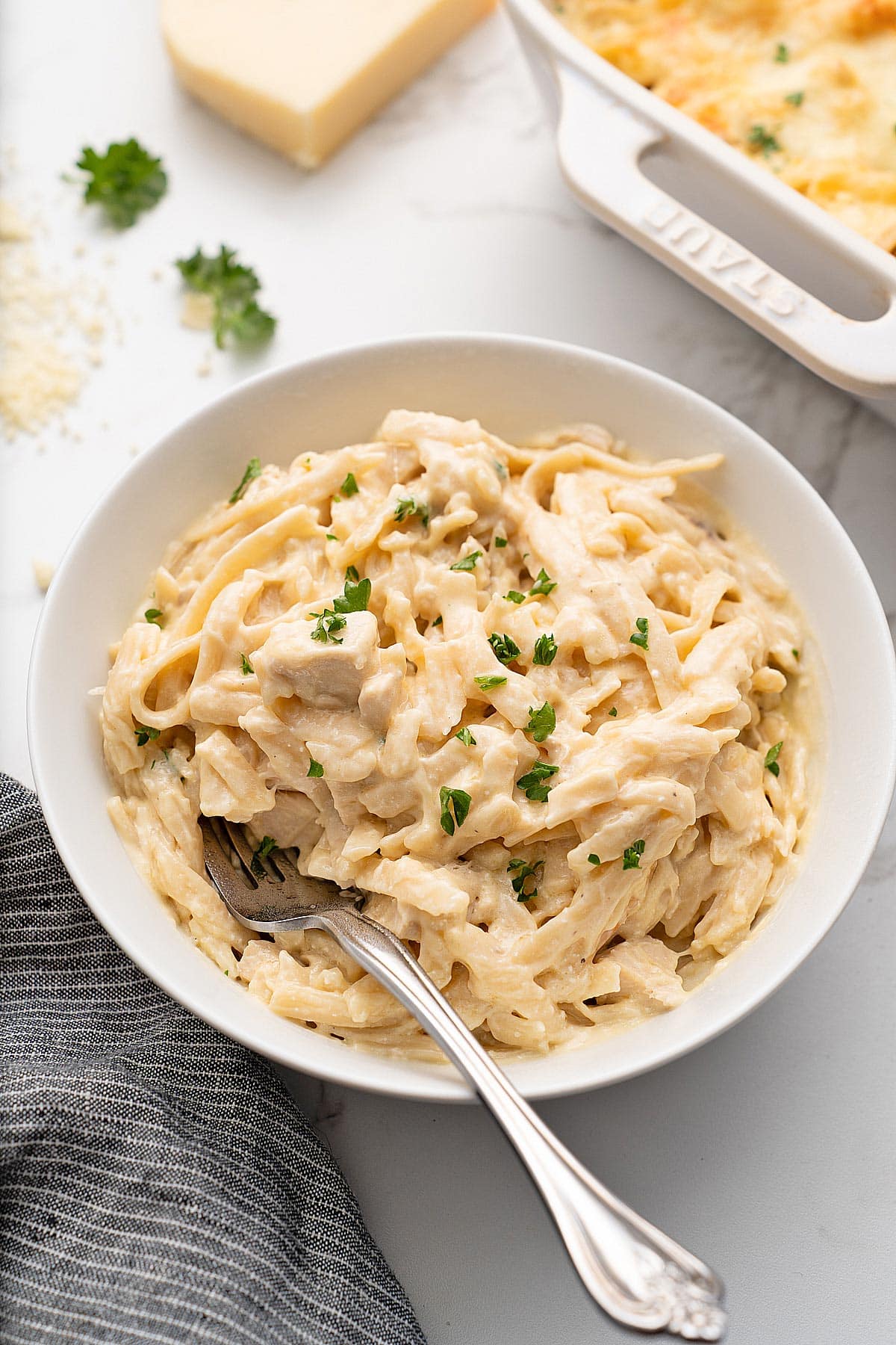 An individual portion of easy chicken tetrazzini topped with fresh chopped parsley in a white bowl.